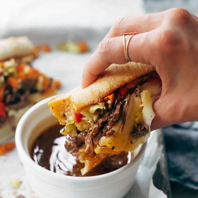 Instant Pot Italian Beef sandwich being dipped in a sauce.