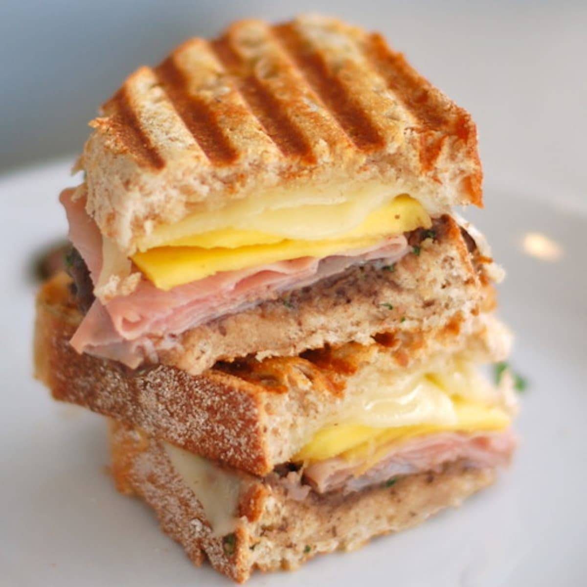 A stack of muevo cubano sandwiches on a white surface.