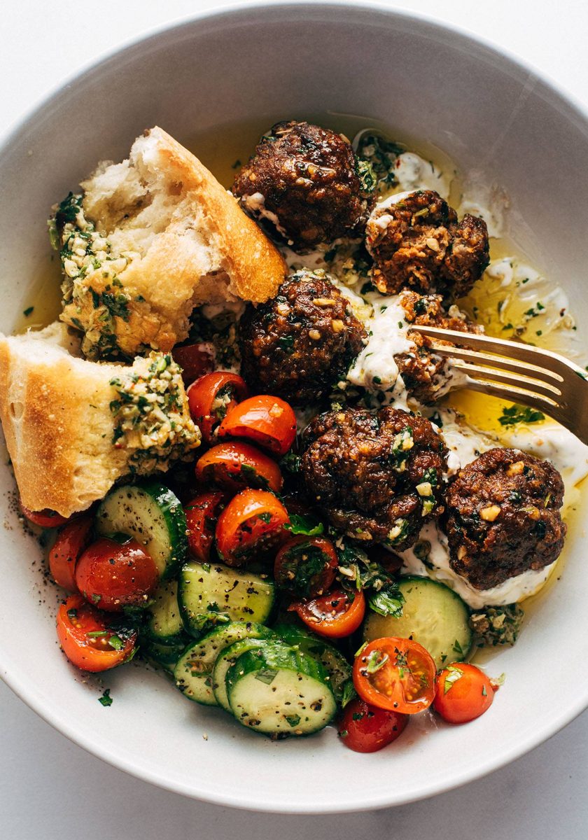 Meatballs in a bowl with a tomato salad and bread
