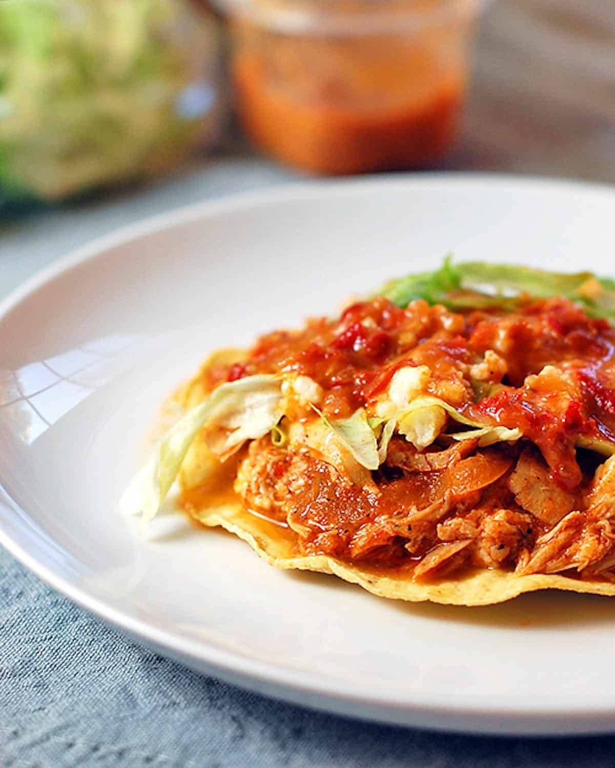 Spicy chicken tostadas on a white plate.